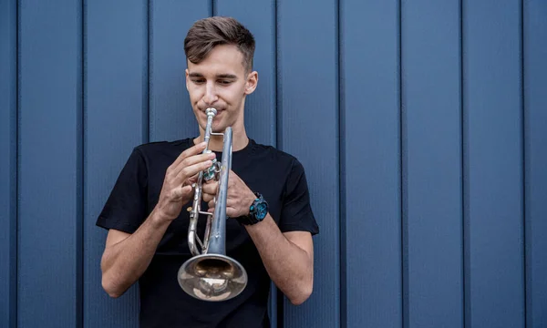 Joven músico callejero tocando la trompeta cerca de la gran pared azul — Foto de Stock