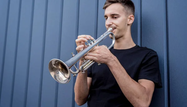Jeune musicien de rue jouant de la trompette près du grand mur bleu — Photo