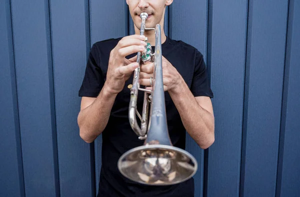 Young street musician playing the trumpet near the big blue wall — Fotografia de Stock