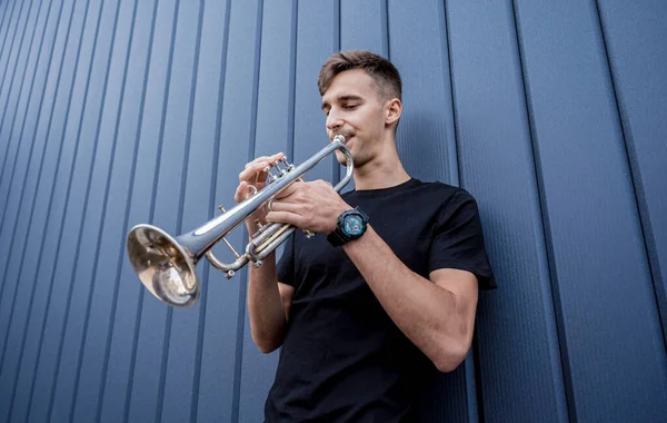 Giovane musicista di strada che suona la tromba vicino al grande muro blu — Foto Stock