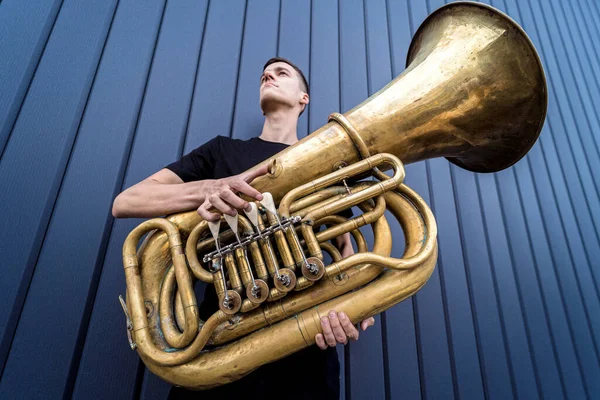 Joven músico callejero tocando la tuba cerca de la gran pared azul — Foto de Stock