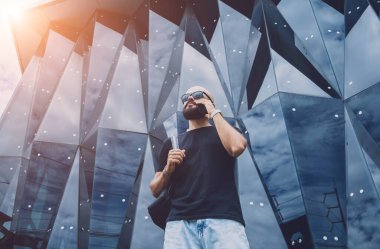 Modadan bir gencin portresi telefonda konuşuyor. Güzel, karanlık şehir arka planında.