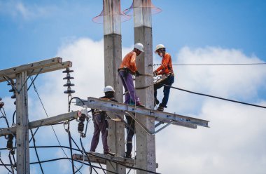Elektrikçiler elektrik direğindeki yüksek voltajlı kabloları tamir ediyorlar.