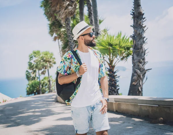 Yaz tatilinde arka planda güzel palmiyeler ve deniz manzaraları olan genç bir gezgin.