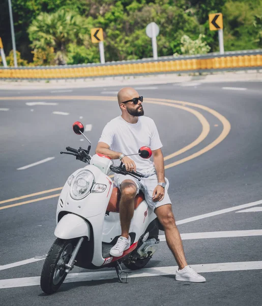 Stylish young man with his motorbike on the road — Photo
