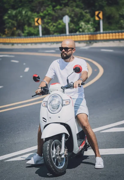 Jovem elegante com sua moto na estrada — Fotografia de Stock