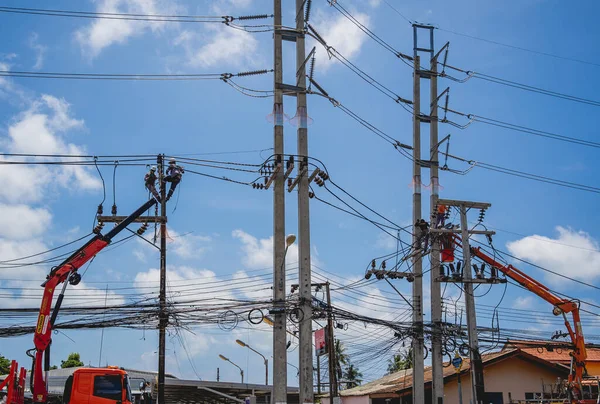 Elektrikçiler elektrik direğindeki yüksek voltajlı kabloları tamir ediyorlar.