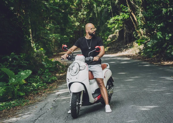 Stylish young man and his motorbike on the road in the jungle — Stock Fotó