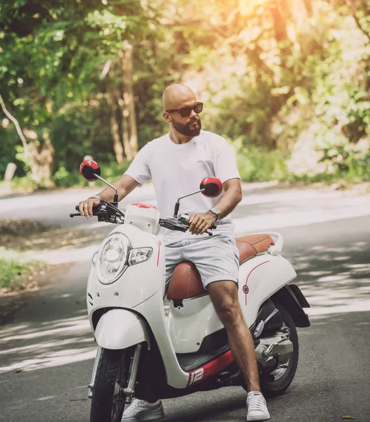Stylish young man and his motorbike on the road in the jungle — Stock Fotó