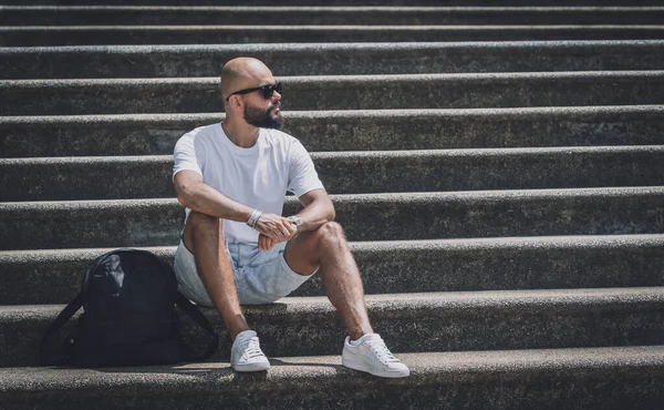 Yalnız genç yakışıklı adam parkta merdivenlerde oturuyor.