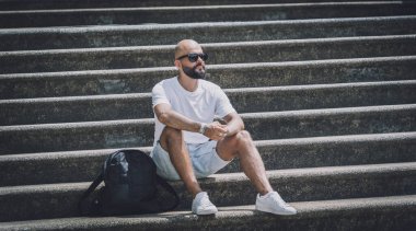Yalnız genç yakışıklı adam parkta merdivenlerde oturuyor.