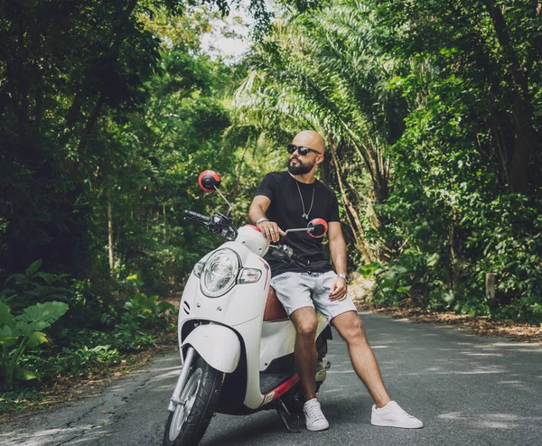 Stylish young man and his motorbike on the road in the jungle — Stock Fotó