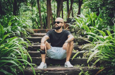 Ormanda yeşil yaprakları olan genç bir adamın portresi.