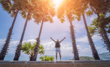 Yaz tatilinde arka planda güzel palmiyeler ve deniz manzaraları olan genç bir gezgin.