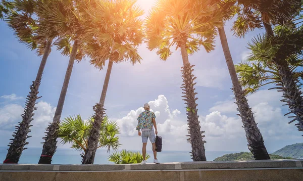 Young traveler man at summer holiday vacation with beautiful palms and seascapes at background — Stockfoto