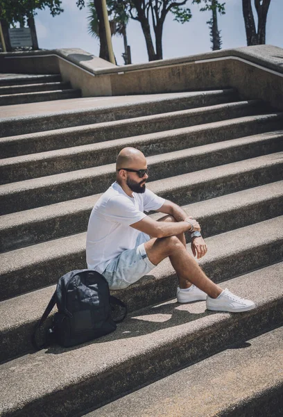 Yalnız genç yakışıklı adam parkta merdivenlerde oturuyor.