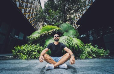 Genç adam ormanda güzel yeşil yapraklarla yoga yapıyor.