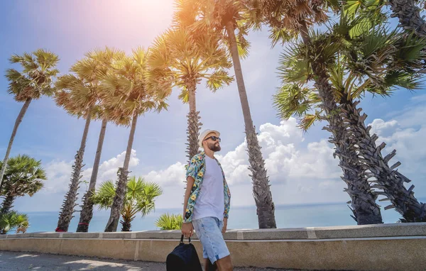 Yaz tatilinde arka planda güzel palmiyeler ve deniz manzaraları olan genç bir gezgin.
