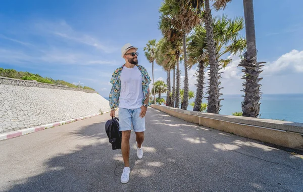 Yaz tatilinde arka planda güzel palmiyeler ve deniz manzaraları olan genç bir gezgin.