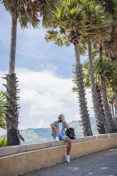 Yaz tatilinde arka planda güzel palmiyeler ve deniz manzaraları olan genç bir gezgin.