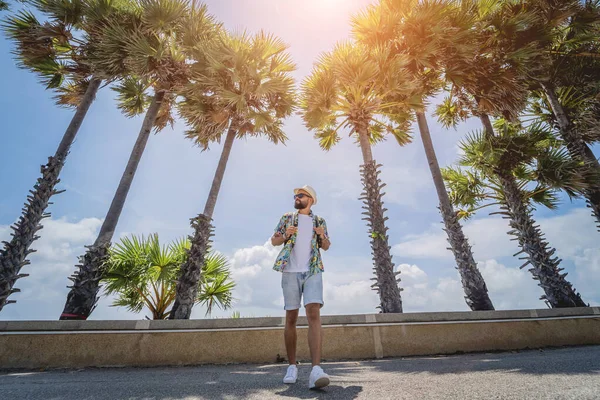 Yaz tatilinde arka planda güzel palmiyeler ve deniz manzaraları olan genç bir gezgin.