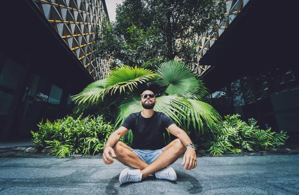 Genç adam ormanda güzel yeşil yapraklarla yoga yapıyor.