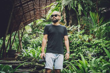 Ormanda yeşil yaprakları olan genç bir adamın portresi.