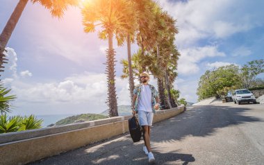 Yaz tatilinde arka planda güzel palmiyeler ve deniz manzaraları olan genç bir gezgin.