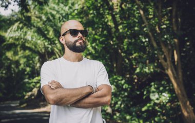 Şık bir genç adam ve motosikleti ormanda yolda.