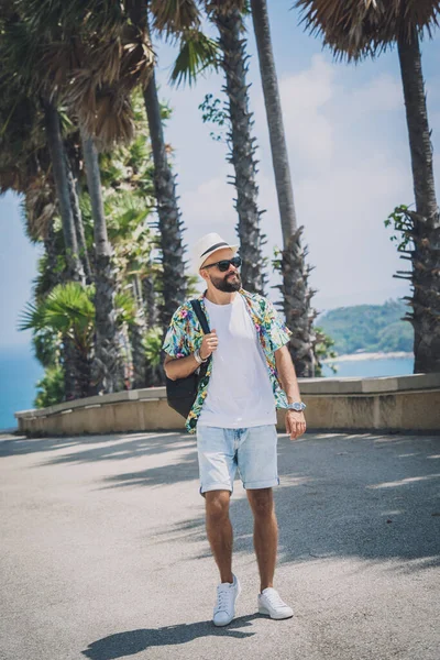 Yaz tatilinde arka planda güzel palmiyeler ve deniz manzaraları olan genç bir gezgin.