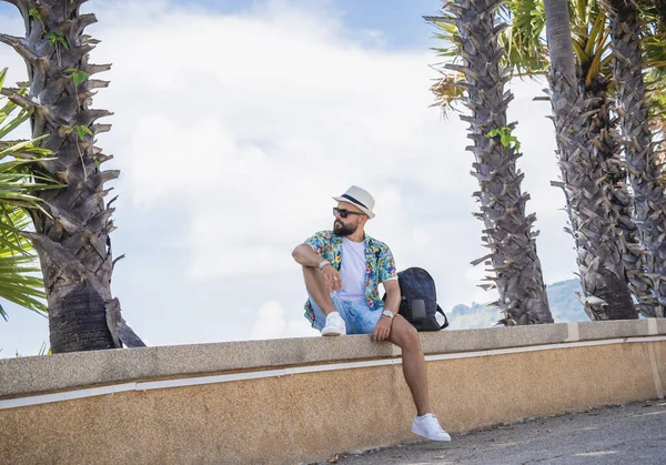 Yaz tatilinde arka planda güzel palmiyeler ve deniz manzaraları olan genç bir gezgin.