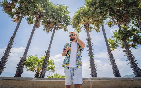 Yaz tatilinde arka planda güzel palmiyeler ve deniz manzaraları olan genç bir gezgin.