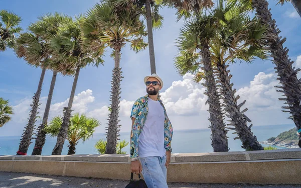 Yaz tatilinde arka planda güzel palmiyeler ve deniz manzaraları olan genç bir gezgin.