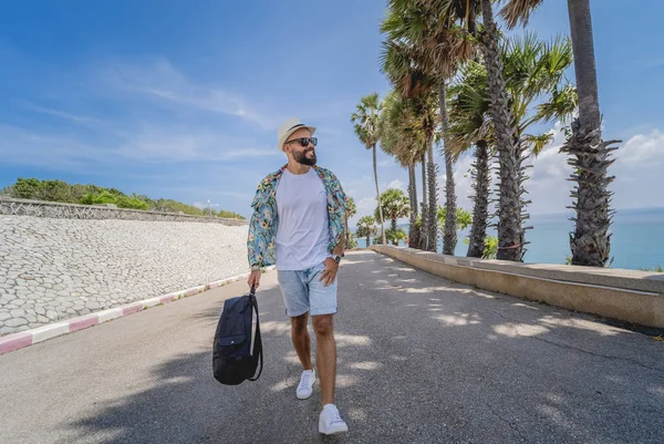 Yaz tatilinde arka planda güzel palmiyeler ve deniz manzaraları olan genç bir gezgin.