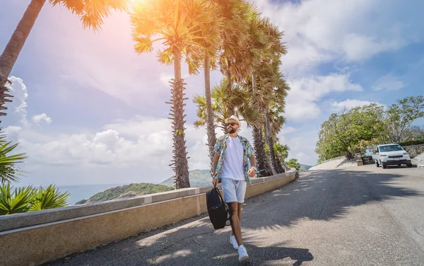 Yaz tatilinde arka planda güzel palmiyeler ve deniz manzaraları olan genç bir gezgin.