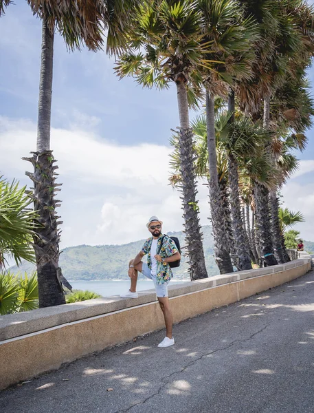 Yaz tatilinde arka planda güzel palmiyeler ve deniz manzaraları olan genç bir gezgin.