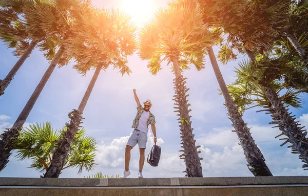 Yaz tatilinde arka planda güzel palmiyeler ve deniz manzaraları olan genç bir gezgin.