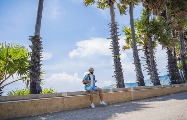Yaz tatilinde arka planda güzel palmiyeler ve deniz manzaraları olan genç bir gezgin.