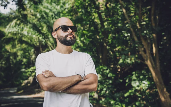 Şık bir genç adam ve motosikleti ormanda yolda.