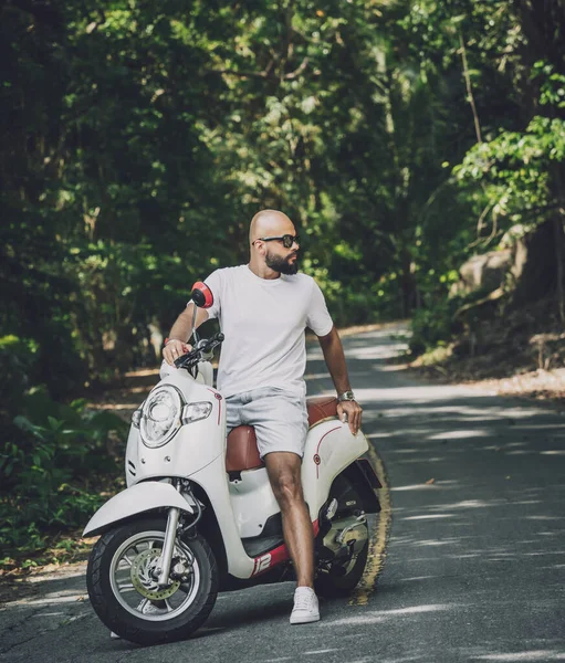 Stílusos fiatalember és motorja az úton a dzsungelben — Stock Fotó