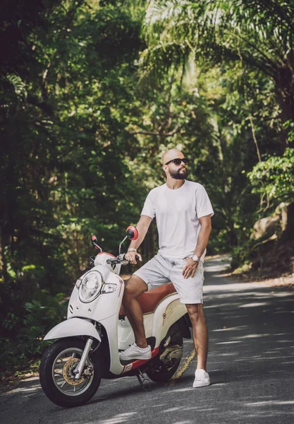 Stylish young man and his motorbike on the road in the jungle — Stock Fotó