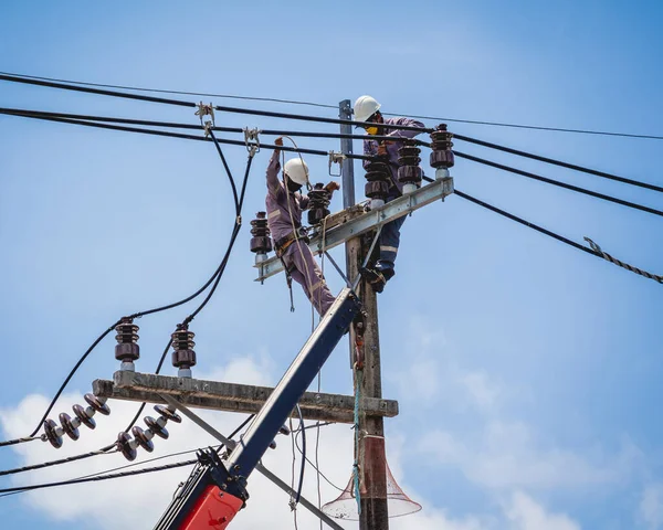 Elektrikçiler elektrik direğindeki yüksek voltajlı kabloları tamir ediyorlar. — Stok fotoğraf