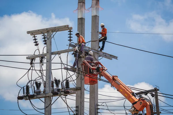 Elektrikçiler elektrik direğindeki yüksek voltajlı kabloları tamir ediyorlar. — Stok fotoğraf