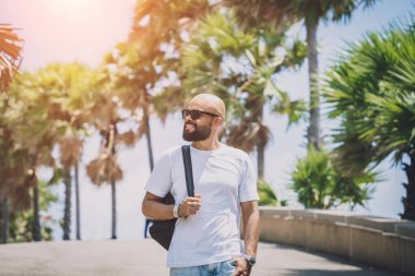 Yaz tatilinde arka planda güzel palmiyeler ve deniz manzaraları olan genç bir gezgin.