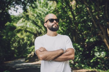 Şık bir genç adam ve motosikleti ormanda yolda.