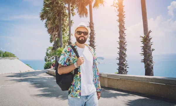 Yaz tatilinde arka planda güzel palmiyeler ve deniz manzaraları olan genç bir gezgin.