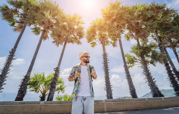 Yaz tatilinde arka planda güzel palmiyeler ve deniz manzaraları olan genç bir gezgin.