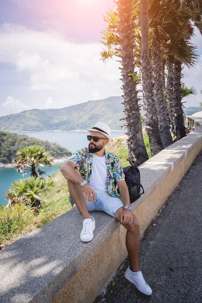 Young traveler man at summer holiday vacation with beautiful palms and seascapes at background — Fotografia de Stock