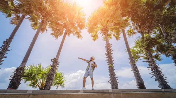 Yaz tatilinde arka planda güzel palmiyeler ve deniz manzaraları olan genç bir gezgin.