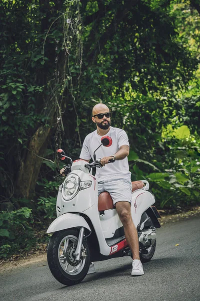 Stylish young man and his motorbike on the road in the jungle — Photo